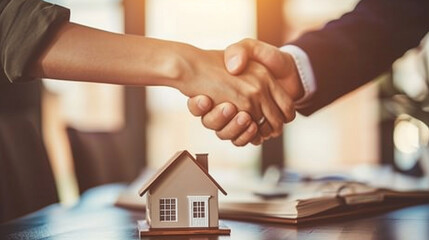 Image of Two People Shaking Hands with a Small House Model in the Background