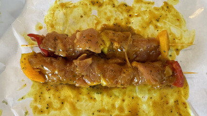 Top view of marinated chicken skewers with colorful vegetables on parchment paper, prepared for grilling or barbecue