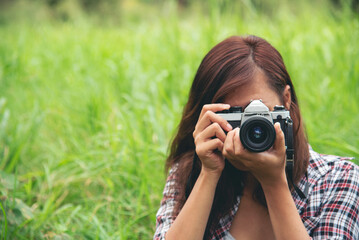 Close up hands Asian Women look at dslr digital camera vintage film style take a photo. Professional female photographer look at picture outdoor. Young woman hands shooting photo in green nature park