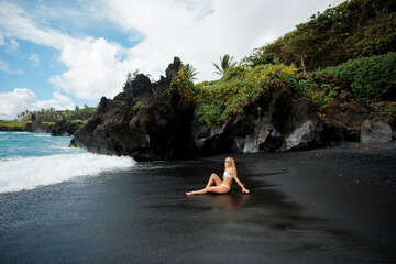 Attractive blonde woman posing on black beach, Maui, Hawaii