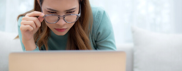 Concentrated young asian woman wearing glasses working on laptop with commitment and ambition...