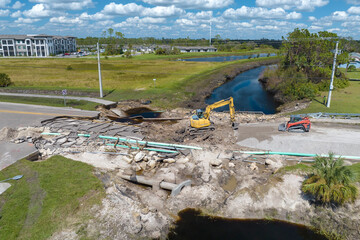 Destroyed bridge after hurricane flooding in Florida. Construction equipment at roadwork site....