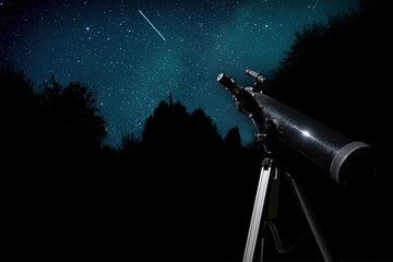 Telescope on a tripod points up to a dark blue night sky filled with stars