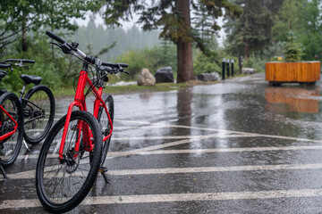 An abandoned bike parked by the side of the road during a rainstorm.