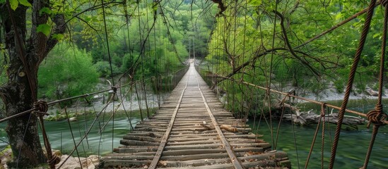 Obraz premium Wooden Suspension Bridge Over The Muddy Spring River