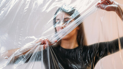 Explore modern life through conceptual art showcasing woman entangled in plastic wrapping to symbolize constraints of contemporary society.