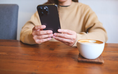 Closeup image of a young woman holding and using mobile phone