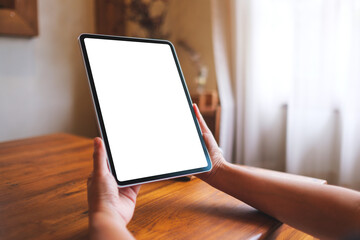 Mockup image of a woman holding digital tablet with blank desktop screen at home