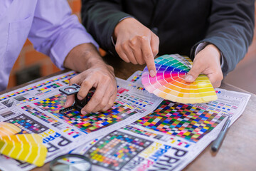 Team graphic designer checking print quality of media graphics proof print and color guides in...