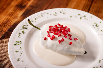 Chiles en Nogada, Typical dish from Mexico. Prepared with poblano chili stuffed with meat and fruits and covered with a walnut sauce, parsley and pomegranate.