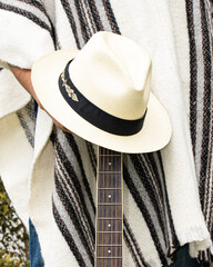 Back view of faceless man with long wavy hair wearing white wool poncho with black stripes and traditional straw hat in Cuenca, Ecuador. Cultural fashion and identity concept.