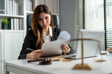 Asian lawyer woman work with hammer and scales of justice in courtroom. 