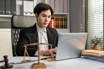 Asian lawyer male work with hammer and scales of justice in courtroom. 