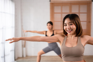 Asian sportswoman friends doing yoga pilates workout together at home.