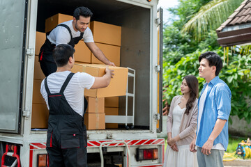 Caucasian delivery man worker delivering package to young couple in house. 