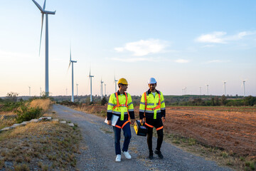 Diverse ethnicity male technicians walking in the wind turbines field.
