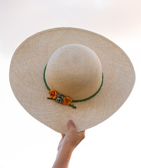 Toquilla straw hat with three small flowers, placed on a light wooden ladder over white background. Elegant handmade Ecuadorian accessory with feminine style and cultural craftsmanship