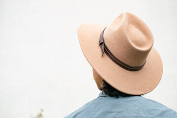 Mestizo male model with curly hair wearing blue shirt and wool cowboy hat with leather decoration. Portrait with blurred natural background and contemporary Andean cultural style.