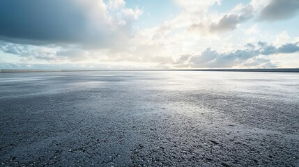 Serene landscape featuring a vast wet surface under a moody sky with dramatic clouds reflecting soft light.
