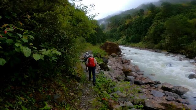 Old men walking on the side of the river in the Himalayas. 