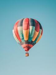 Obraz premium A vibrant hot air balloon carries an adventurer high above, soaring through a pristine sky.