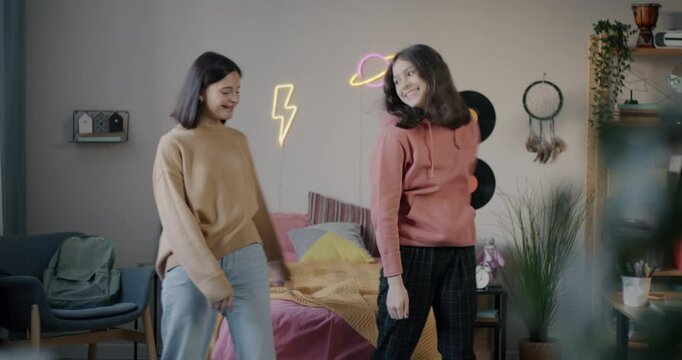 Teenage girl dancing with mother adult woman laughing enjoying music spending time together at home. Family relationship and modern lifestyle concept.