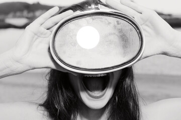 A woman holds a vintage mirror in front of her face, revealing her expressive mouth and eyes, set against a blurred outdoor background