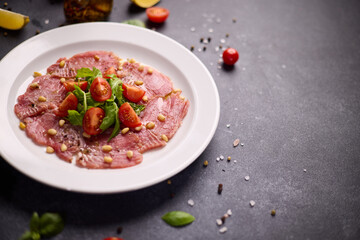 cooking tuna carpaccio - Fresh raw tuna fillet with olive oil and pine nuts on white ceramic plate