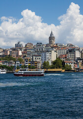 Obraz premium Istanbul, Turkey - August 10, 2024: Panoramic view of Galata Tower and ancient architecture in the historic part of the city on the shores of the Sea of ​​Marmara and tourist boats on a sunny summer