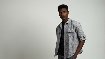 Fototapeta premium teen stunning black hair subsaharan african man with generic shirt model portrait standing straight on a white wall for ad concept space for text