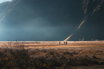 A super wide shot of people in a misty mountain valley at sunrise.