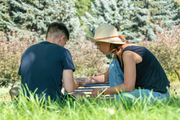 Mom and a teenager interact together by collecting a wooden ship in the park in the summer.
