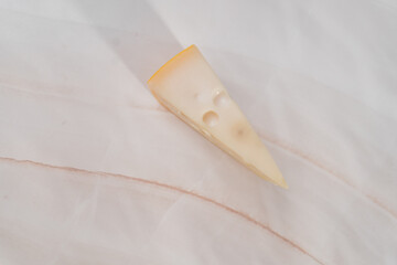 A large piece of cheese with holes on a light white table