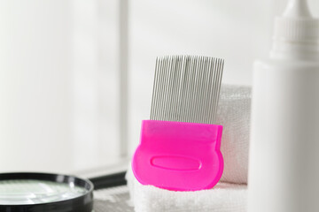 Lice treatment product next to a nit comb and magnifying glass