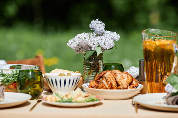 Table set outdoors with various freshly prepared dishes and drinks arranged beautifully. A bouquet of flowers adds elegance to the dining experience