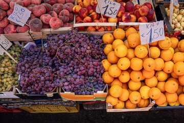 Colorful fruit market stall: fresh peaches, nectarines, grapes, oranges with price tags in euros