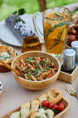 Table filled with delicious spread of summer foods, including pasta salad, garlic bread, and infused lemon water vibrant and inviting ambiance perfect for outdoor gatherings