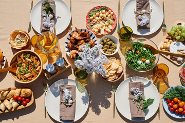 An overhead view of a beautifully arranged summer brunch table featuring various delicious dishes,...