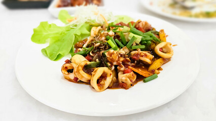 Stir Fried Squid with Chilli Paste. Thai Food. Fried Squid served with spicy sweet vegetables. Seafood octopus served and vegetables and red sauce.