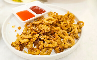 Crispy breaded squid rings. Deep-fried crispy squid with sweet sauce on in plate on table. Crunchy Fried squid appetizer, served with beer.