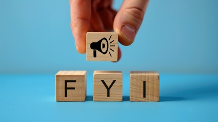 Hand put the speaker on FYI wooden block character on blue background. Information announcement concept.