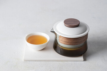 Crystal teapot and white bowl cup with herbal tea on the podium, menu, ads, product card