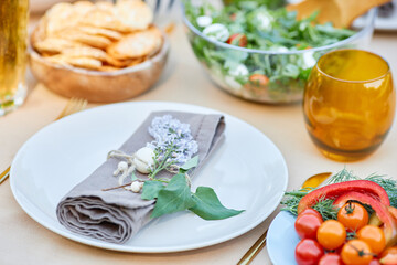 Table prepared for formal dinner with neatly arranged plates, napkins wrapped with flower arrangements, salads, and breads, creating an elegant dining atmosphere