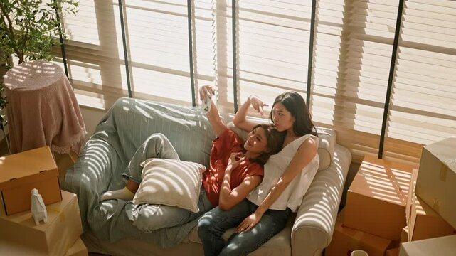 Young same sex female(girl love or Lesbian) couple moving to new house.Happy family two asian sisters having fun at new home cardboard boxes in apartment.LGBTQ+ Family Moving house relocation concept.