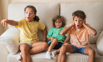 Three Children Watch TV At Home. Their Excited And Positive Emotions Reflect The Joyful Energy Of A...
