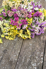 Multicolored kermek and statice flowers on rough wooden background. floral background on rough boards.