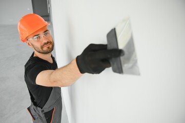 man drywall worker or plasterer putting mesh tape for plasterboard on a wall using a spatula and...
