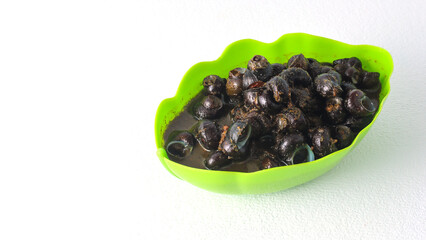 A bowl filled with cooked river snails (tutut) in a spicy sauce. Tutut is a popular dish in some regions of Indonesia, made from freshwater snails.