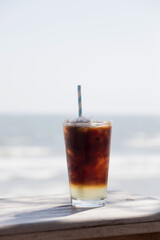 Refreshing iced coffee served on a sunny day by the beach, perfect for a summer drink on a relaxing afternoon.