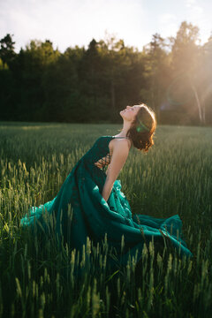Joyful teen girl in a prom dress enjoying sunset in a field